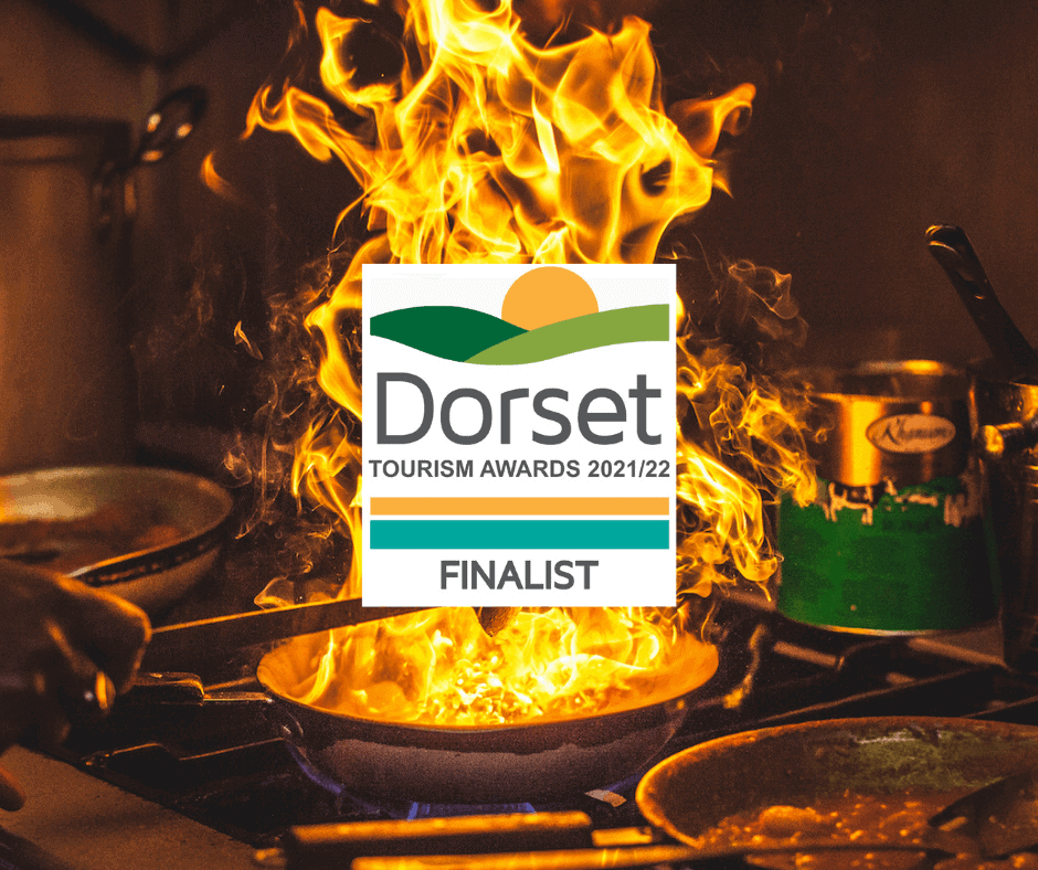 Flames over a pan at Shalims Finalist with the Dorset Tourism Awards logo over the photo